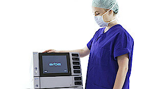 A woman standing next to Erbe product VIO 3 and showing the setup.