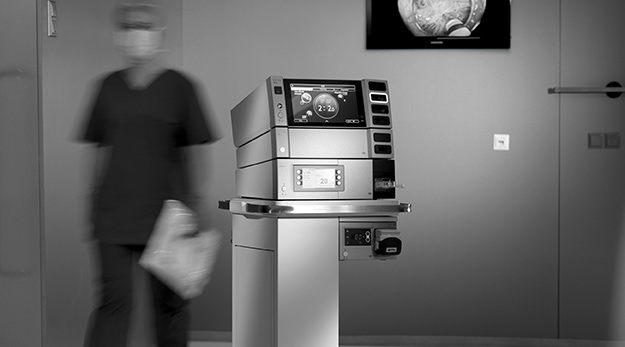 VIO 3n electrosurgical workingstation positioned in an operating room, with a blurred medical professional walking by in the background.